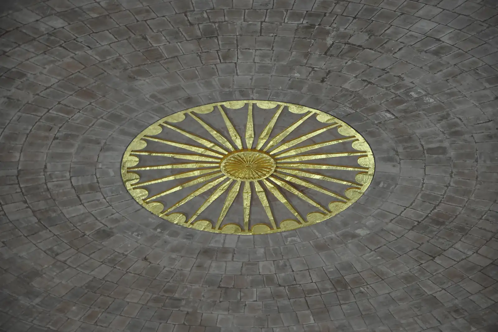 The apex of the stone dome inside the Global Vipassana Pagoda, concentric rings of stone blocks around a gilded Dhamma wheel