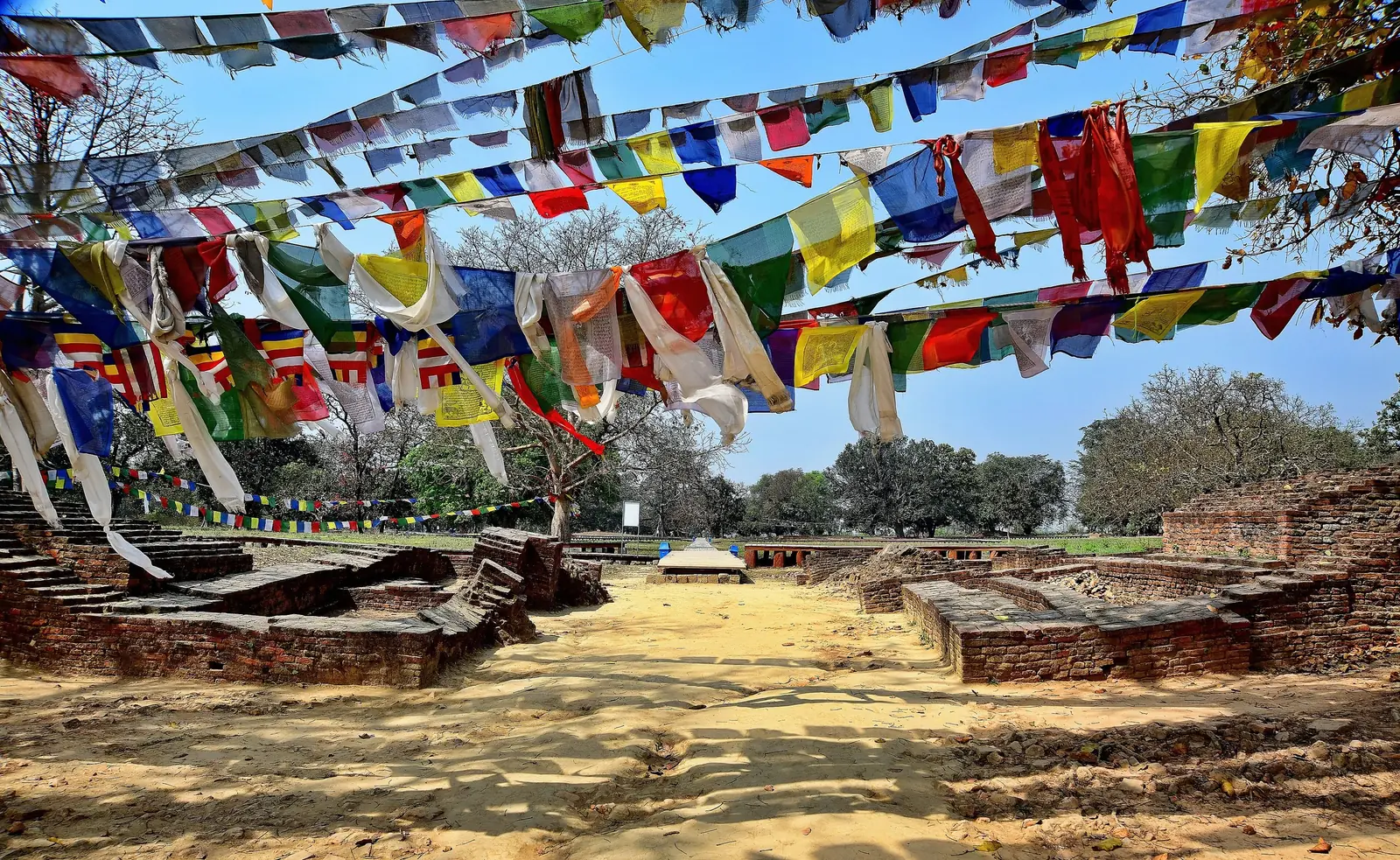 Prayer flags strung above excavated brick foundations at Tilaurakot