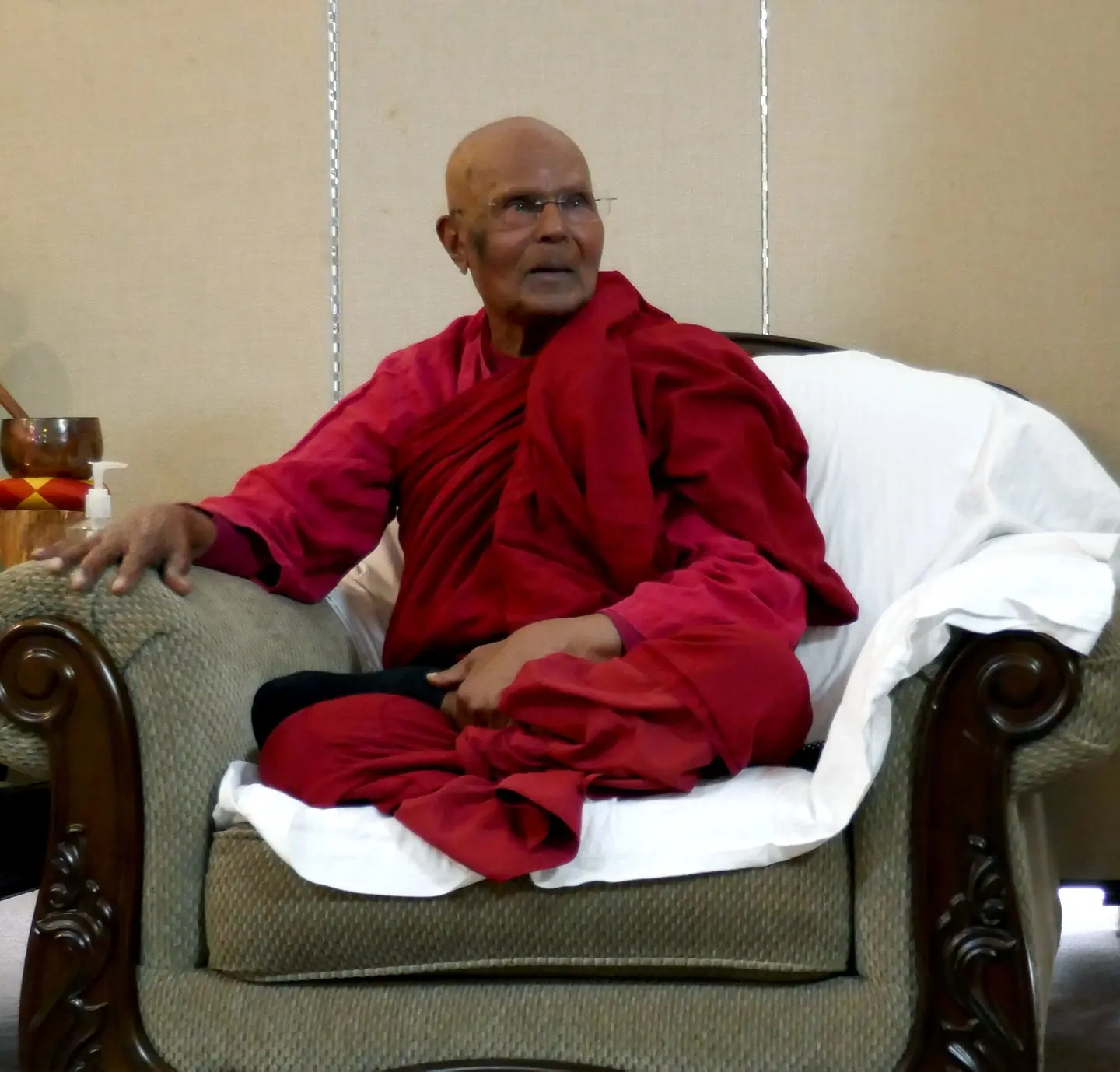 Bhante Henepola Gunaratana, an elderly Sri Lankan monk in red robes, seated in an armchair and smiling