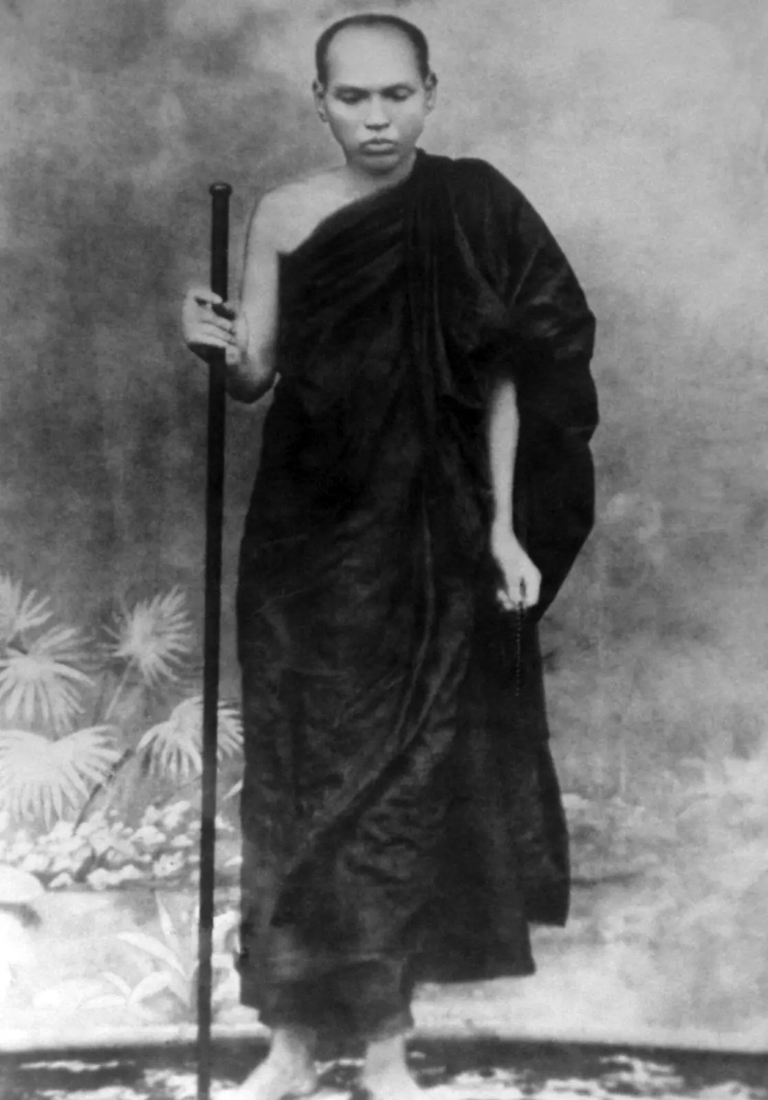 Historic black-and-white photograph of Ledi Sayadaw standing in dark robes and holding a staff