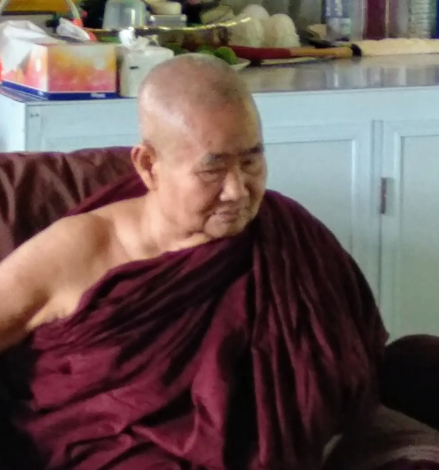 Pa-Auk Sayadaw, an elderly Burmese monk in maroon robes, seated in an armchair and looking to one side